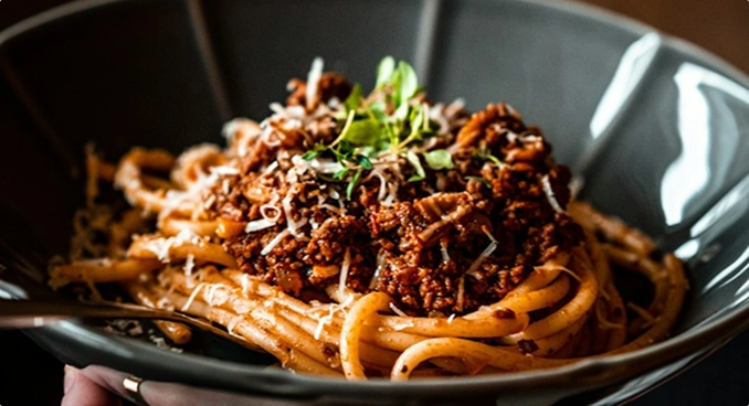 A close-up of a richly sauced pasta dish finished with fresh herbs.