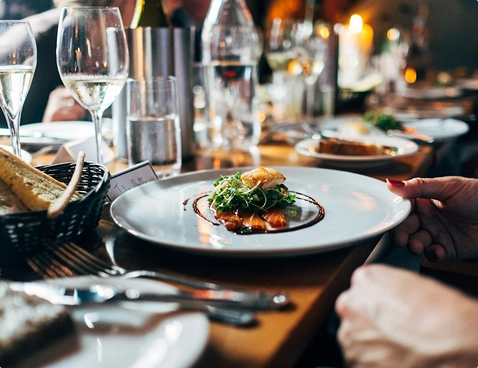 A plated restaurant dish being served at an elegant table set with glassware.